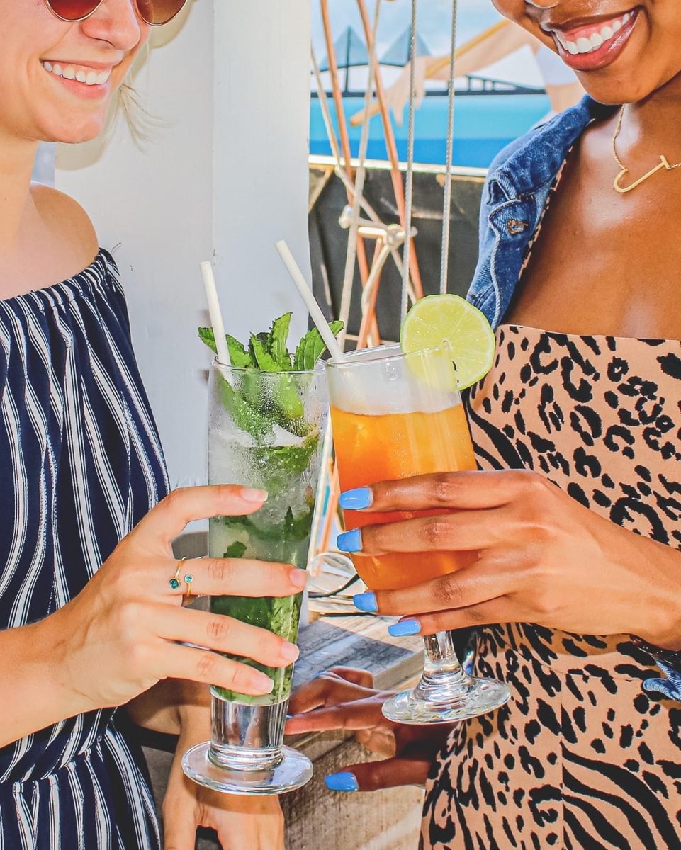 Two guests toasting tall tropical cocktails.