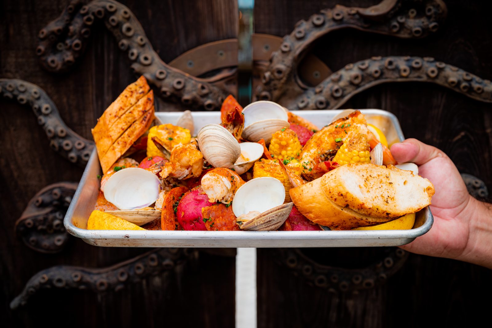 A tray of grilled seafood held over a table wrapped in an octopus-tentacle base.