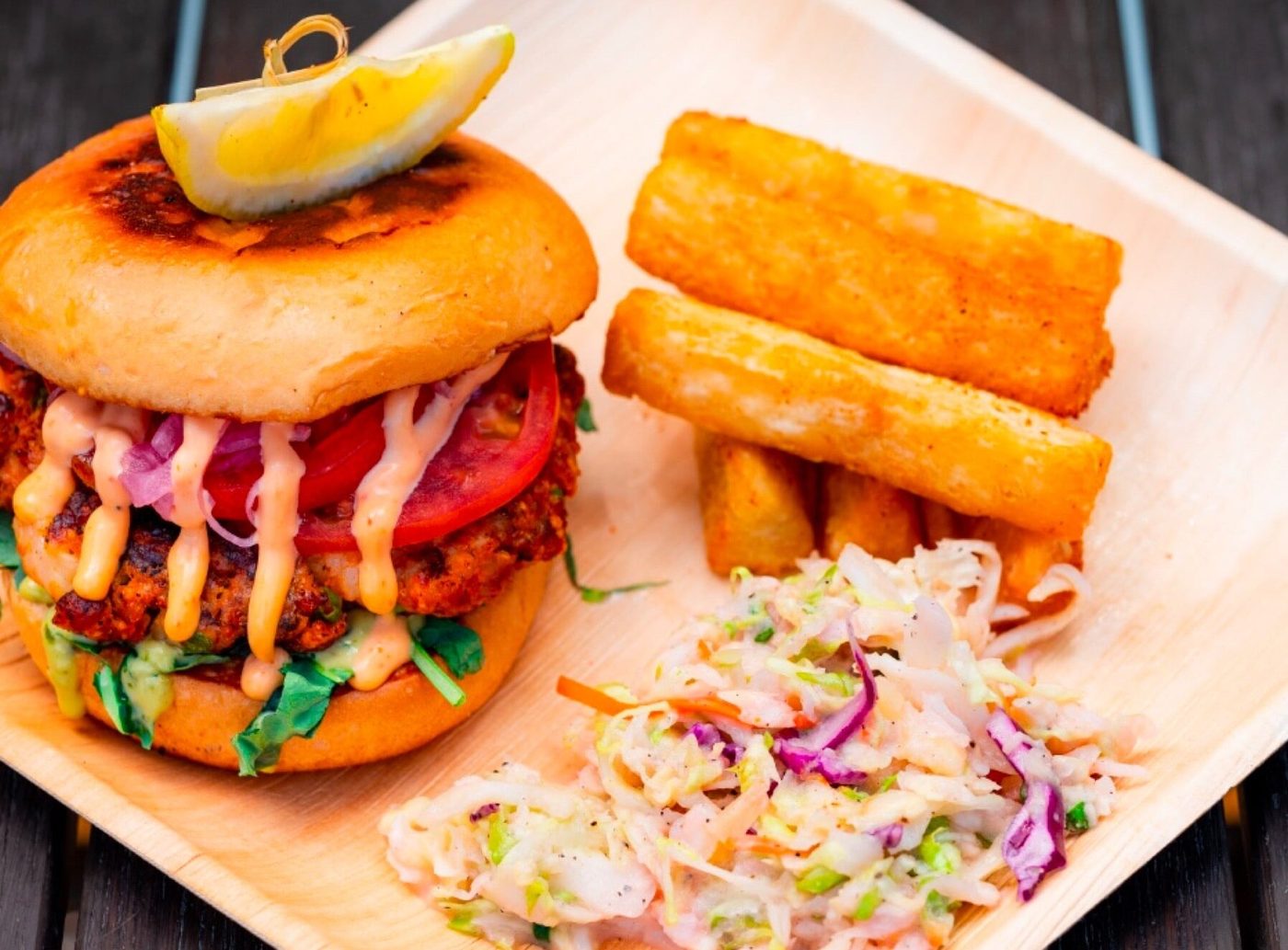 A smoked shrimp burger with slaw and fried sides.